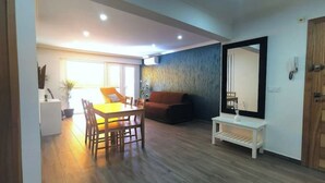 En moderne stue med spiseområde, sofa, sofabord og et stort spejl.