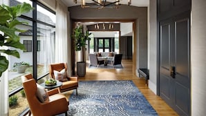 A modern interior with a dining area, a large window, and a chandelier. - Hotel Hartness (Greenville)