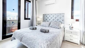 Een slaapkamer met een groot bed, een nachtkastje, een raam en uitzicht op het omliggende landschap.
