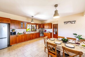 Una cocina moderna con armarios de madera, una mesa de comedor preparada para cuatro personas y un refrigerador.