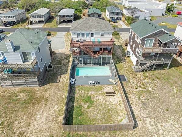 A residential area with multiple houses, a swimming pool, and a fenced yard. - Beach Bum'n: Private Pool | 3-Min Walk to Beach (Nags Head)