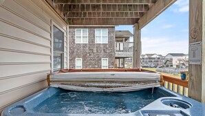 Un jacuzzi en una terraza de madera con vista a un edificio residencial al fondo.