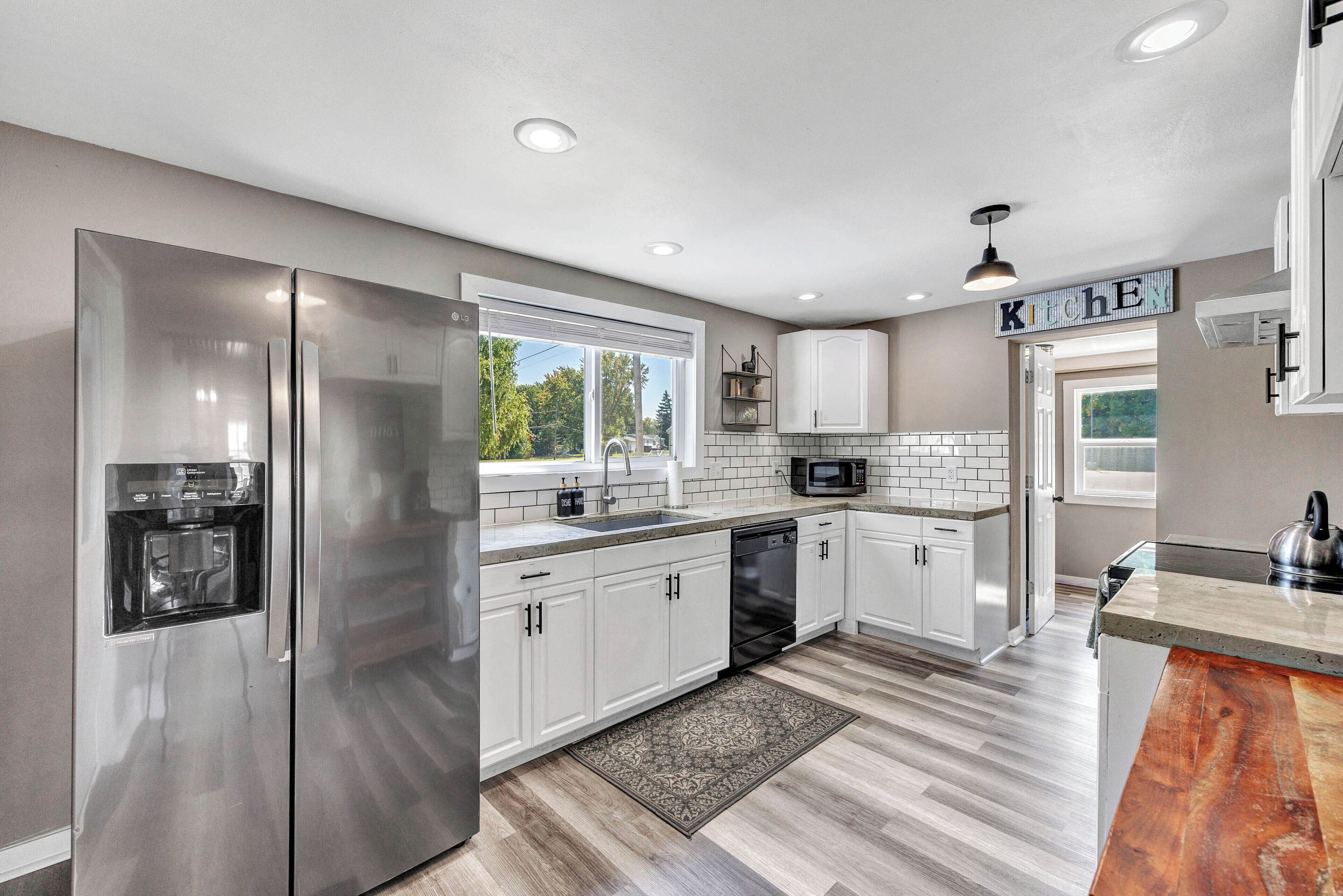 A modern kitchen with white cabinets, stainless steel appliances, and a built-in microwave.