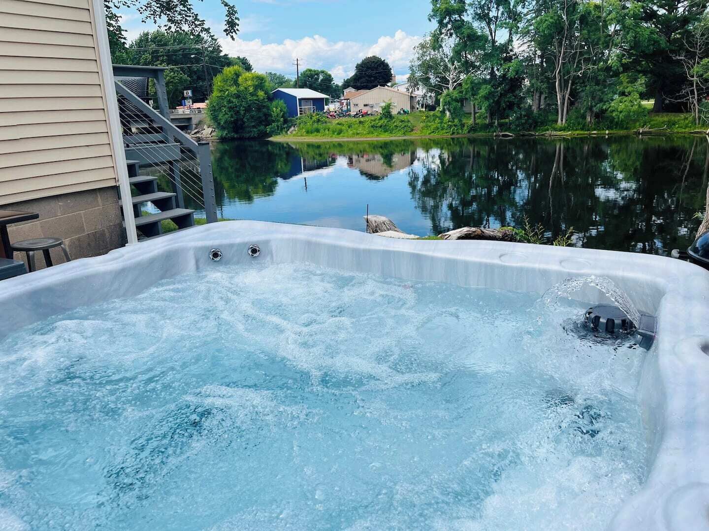 Uma banheira de hidromassagem com vista para um lago calmo e edifícios residenciais ao fundo.