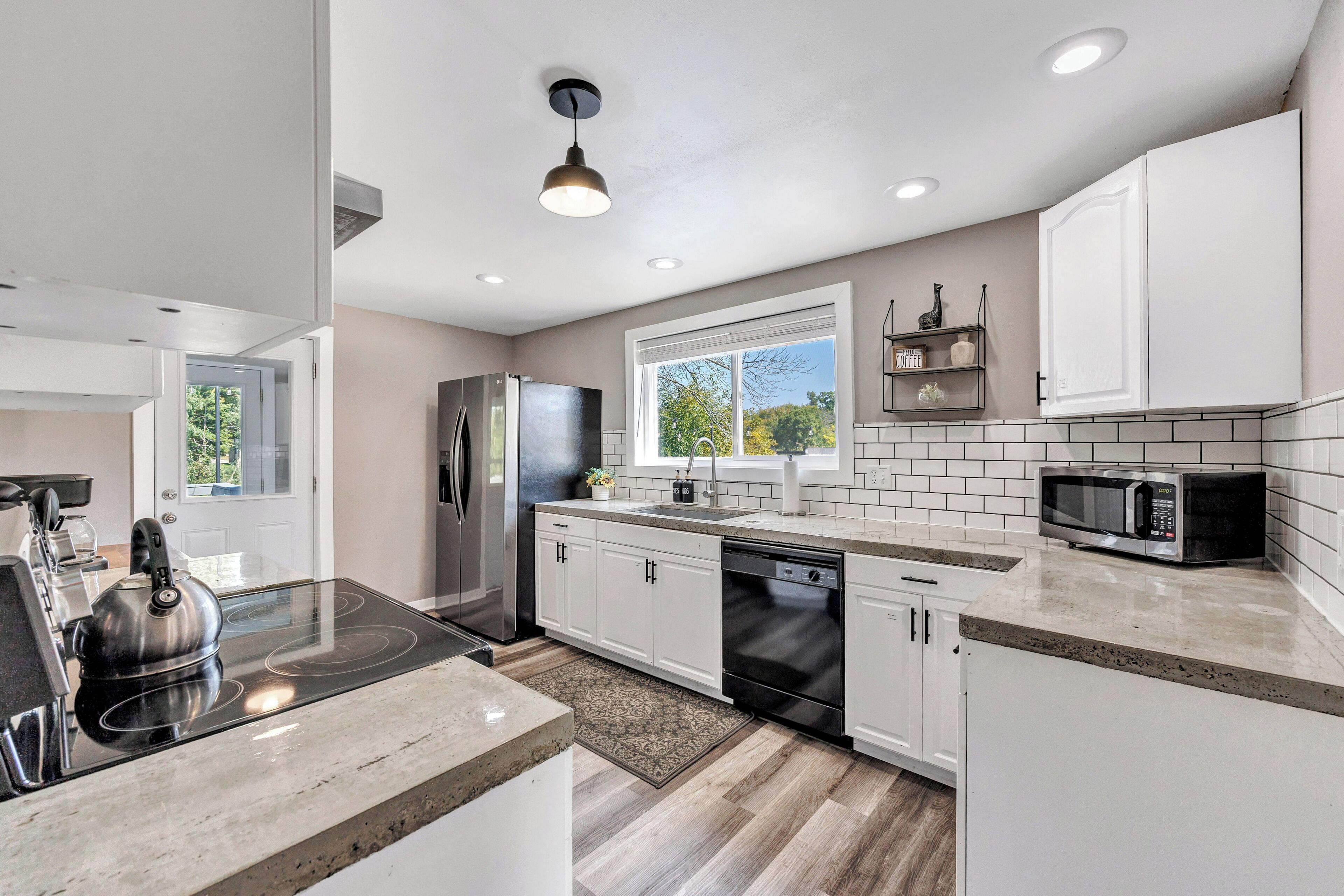 A modern kitchen with white cabinets, a stainless steel refrigerator, a microwave, and a dishwasher.