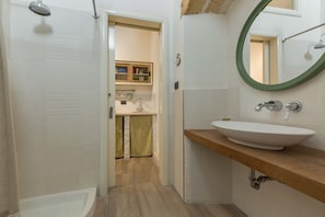 A bathroom with a bathtub, a sink with a wooden countertop, a mirror with a green frame, and a showerhead. - 2513 Antico Palazzo Rolli - Stanza Delle Botti (Galatone)