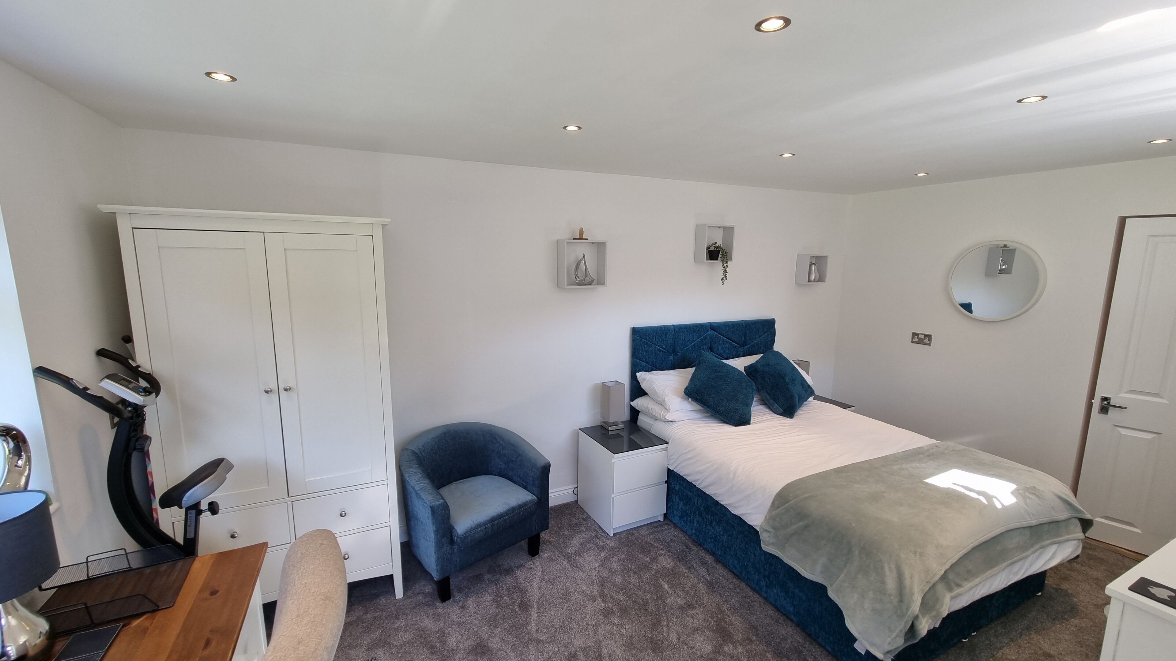 A bedroom with a bed, a chair, a desk, and a wardrobe.