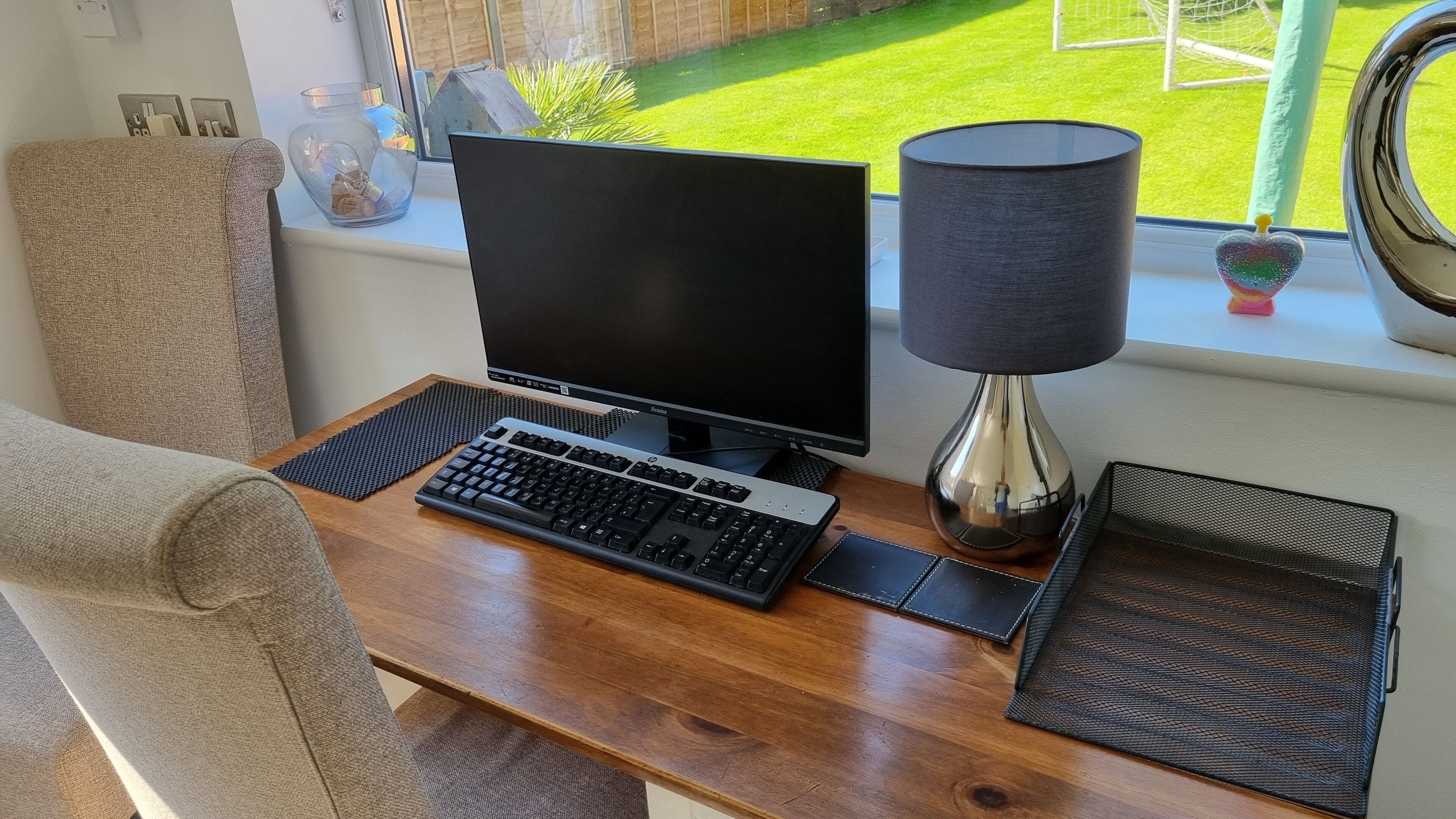 Un bureau d’ordinateur avec un écran, un clavier et une lampe.