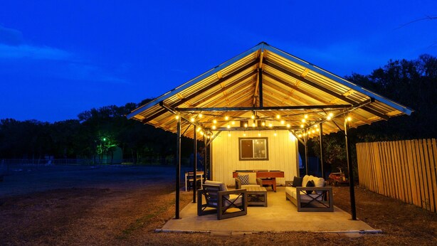 A covered outdoor seating area with string lights, a table, and chairs. - King Suite, Family Friendly & Outdoor Pool Table (Austin)