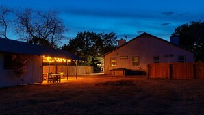 A backyard with a covered patio, a wooden fence, and a house. - King Suite, Family Friendly & Outdoor Pool Table (Austin)