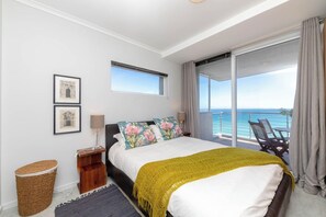A bedroom with a bed, a bedside table, a lamp, a waste basket, and a view of the ocean. - West Coast Horizon Retreat (Cape Town)
