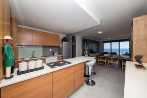 Een moderne keuken met houten kastjes, een wit aanrecht en een bar met krukken.