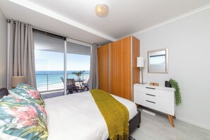 A bedroom with a bed, a dresser, a mirror, and a view of the ocean. - West Coast Horizon Retreat (Cape Town)