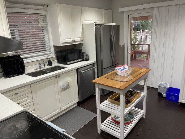 Una cocina moderna con armarios blancos, un refrigerador de acero inoxidable, un microondas y una tostadora.