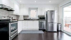 Una cocina moderna con armarios blancos, electrodomésticos de acero inoxidable y suelo de madera oscura.