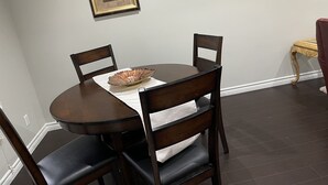 Un comedor con una mesa redonda, cuatro sillas, un cuenco decorativo y obras de arte enmarcadas en la pared.