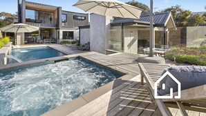 Ein moderner Poolbereich im Freien mit Whirlpool, Liegestühlen und Sonnenschirmen.