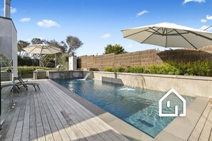 A modern outdoor swimming pool with a wooden deck, lounge chairs, and umbrellas. - Cambridge Gardens *1 NIGHT FREE* Luxury in Sorrento with Spa & Solar Heated Pool (Sorrento)