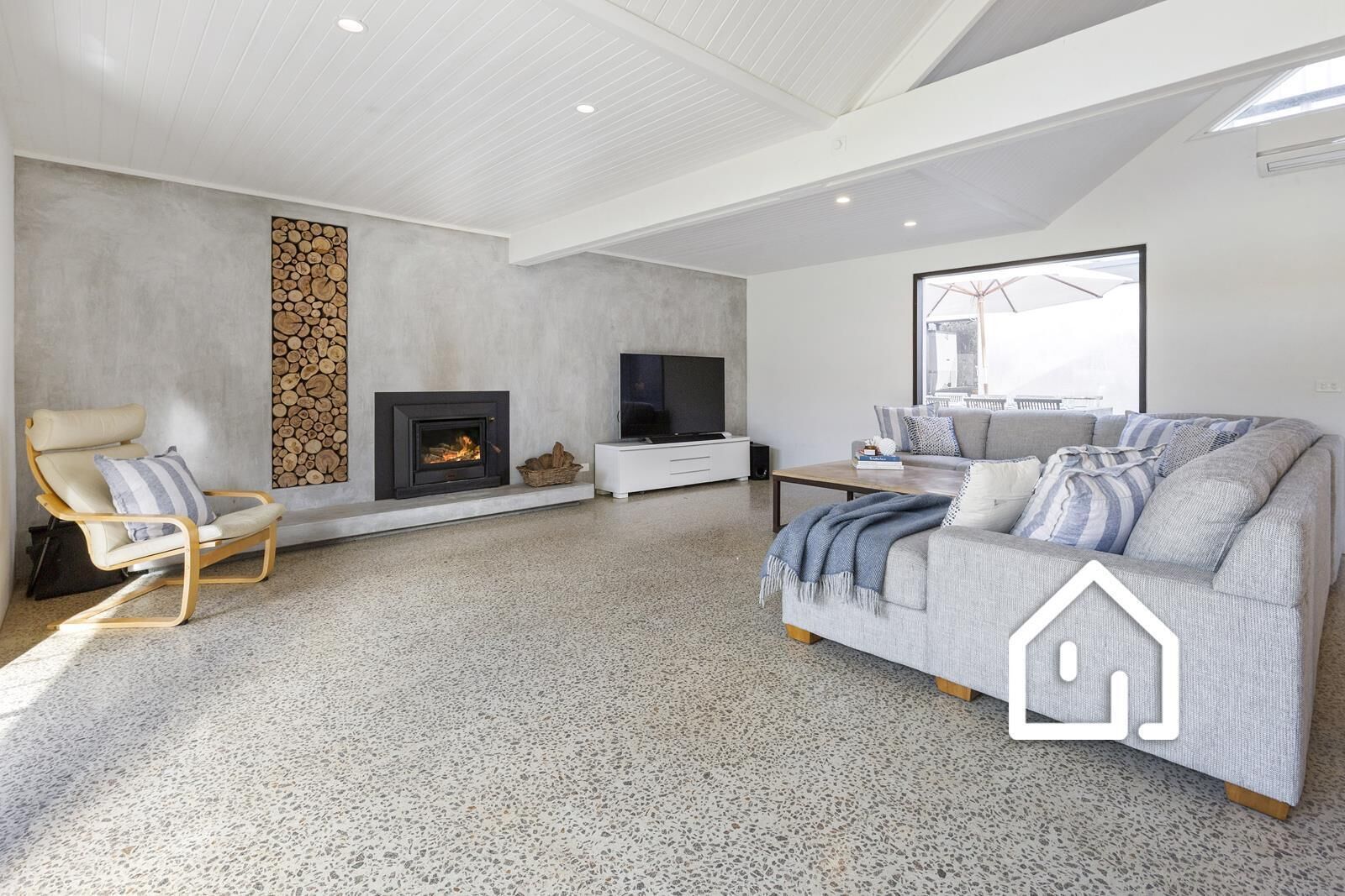 A modern living room with a fireplace, a sofa, a TV, and a stone wall.