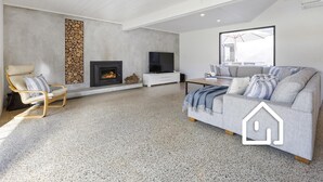 Ein modernes Wohnzimmer mit Kamin, einer Couch, einem Fernseher und einer Steinwand.
