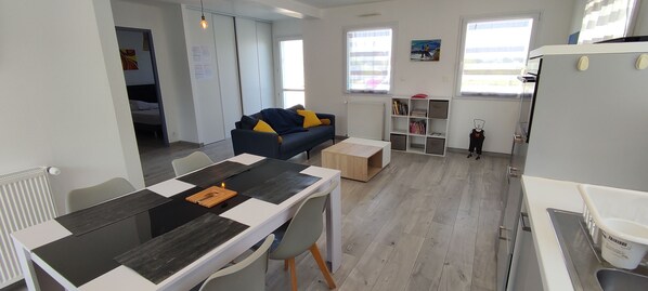 A modern living room with a dining table, sofa, and a child’s play area.
