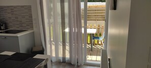 Une cuisine au design moderne, avec une porte-fenêtre coulissante donnant sur un patio extérieur agrémenté d’une clôture en bois et d’une chaise bleue.