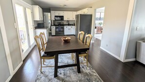 A modern kitchen with white cabinets, a dark wooden dining table, and a rug. - Spacious 3 Bedroom, 5 minutes from Downtown Cincinnati (Highland Heights)