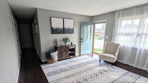 A spacious living room with a large rug, a blue door, and a view of the outdoors. - Spacious 3 Bedroom, 5 minutes from Downtown Cincinnati (Highland Heights)