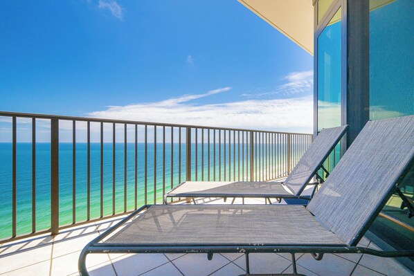 A balcony with two sun loungers overlooking the ocean.