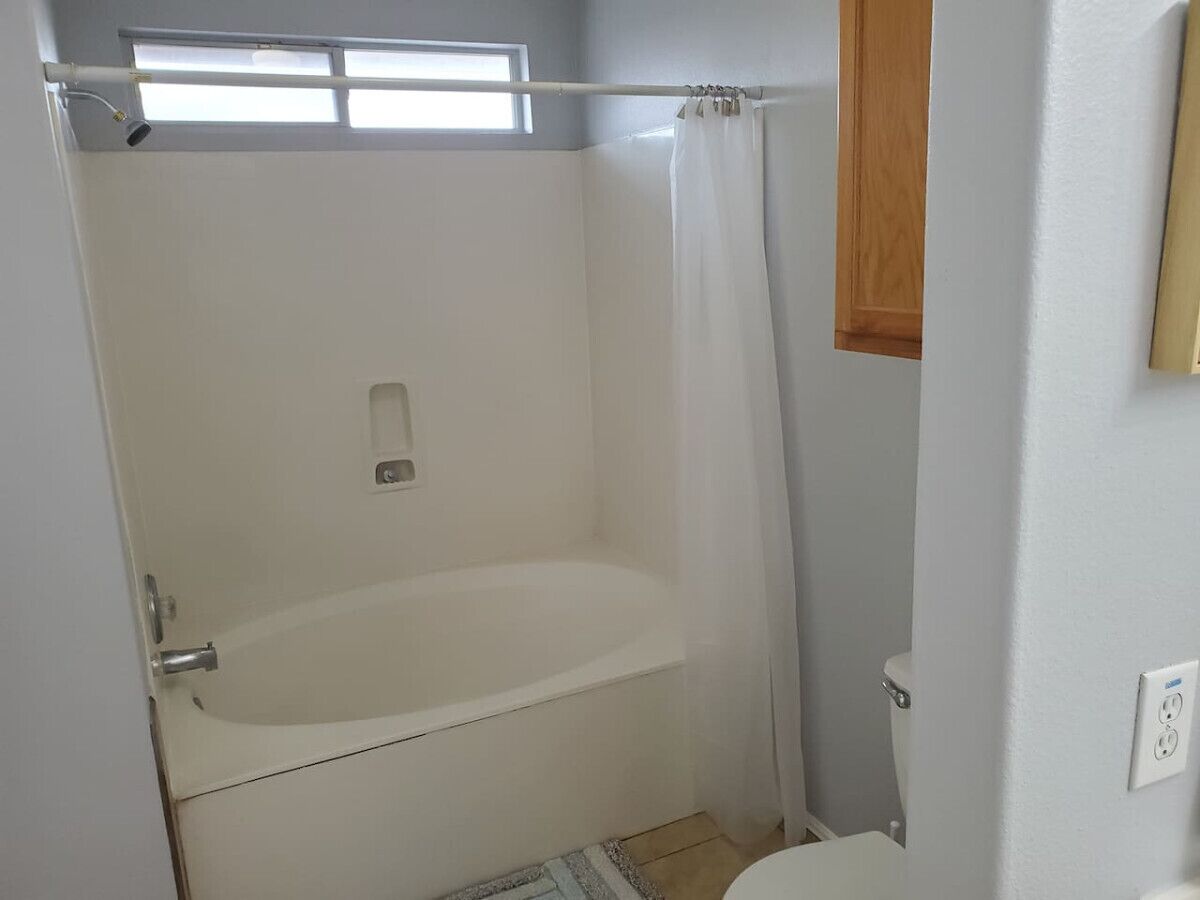 Ein Badezimmer mit einer Badewanne, einer Toilette und einem Fenster.
