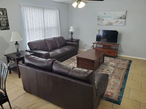 A living room with a sofa, a coffee table, a TV, a lamp, and a rug. - Fiesta Texas, Sea World Minutes Away Quiet area (San Antonio)