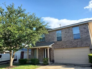 A two-story house with a garage, a covered porch, and a tree in the front yard. - Fiesta Texas, Sea World Minutes Away Quiet area (San Antonio)