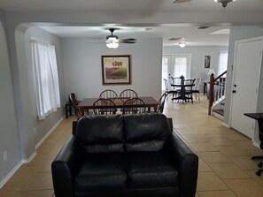 A living room with a black leather sofa, a dining table with chairs, a ceiling fan, and a staircase leading to another level. - Fiesta Texas, Sea World Minutes Away Quiet area (San Antonio)