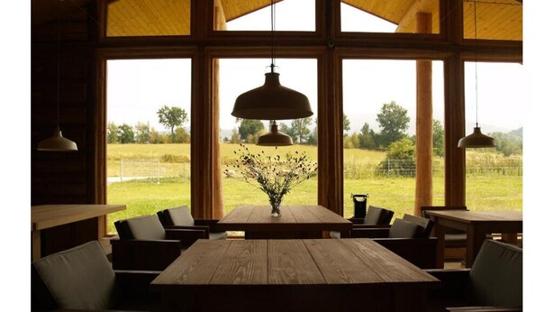 A rustic wooden dining area with large windows, a hanging pendant light, and a vase with flowers on the table. - Quadruple Room with Bathroom (Sciegny)