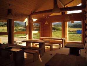 Enjoy panoramic views of the lush landscape from the cabin's large windows, where you can dine and relax on wooden benches and tables.