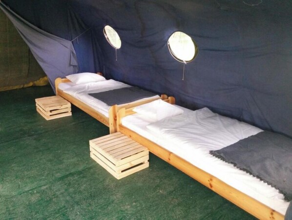 Two wooden beds with white linens and gray pillows, each with a small wooden stool. - Quadruple Room with Bathroom (Sciegny)