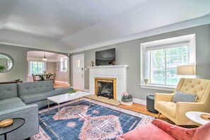 A living room with a fireplace, grey sofas, a coffee table, and a patterned rug. - Idyllic Springfield Haven w/ Screened Porch! (Springfield)