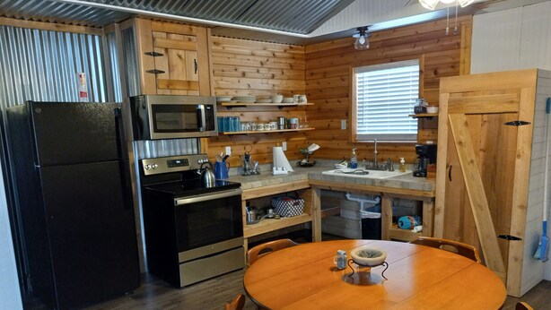 A compact kitchen with a refrigerator, microwave, stove, and wooden cabinets. - Country Living with Kyle Field 30 minutes away (SOMERVILLE)