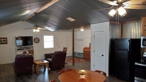 A spacious living room with a wooden dining table, comfortable seating, a television, and a kitchen area with a refrigerator and microwave. - Country Living with Kyle Field 30 minutes away (SOMERVILLE)