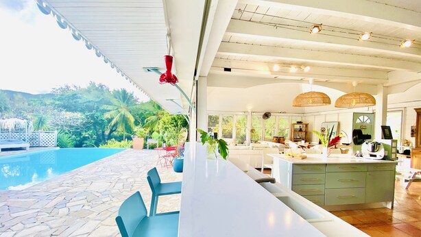 Une cuisine moderne avec un coin bar, une terrasse en pierre et une piscine.