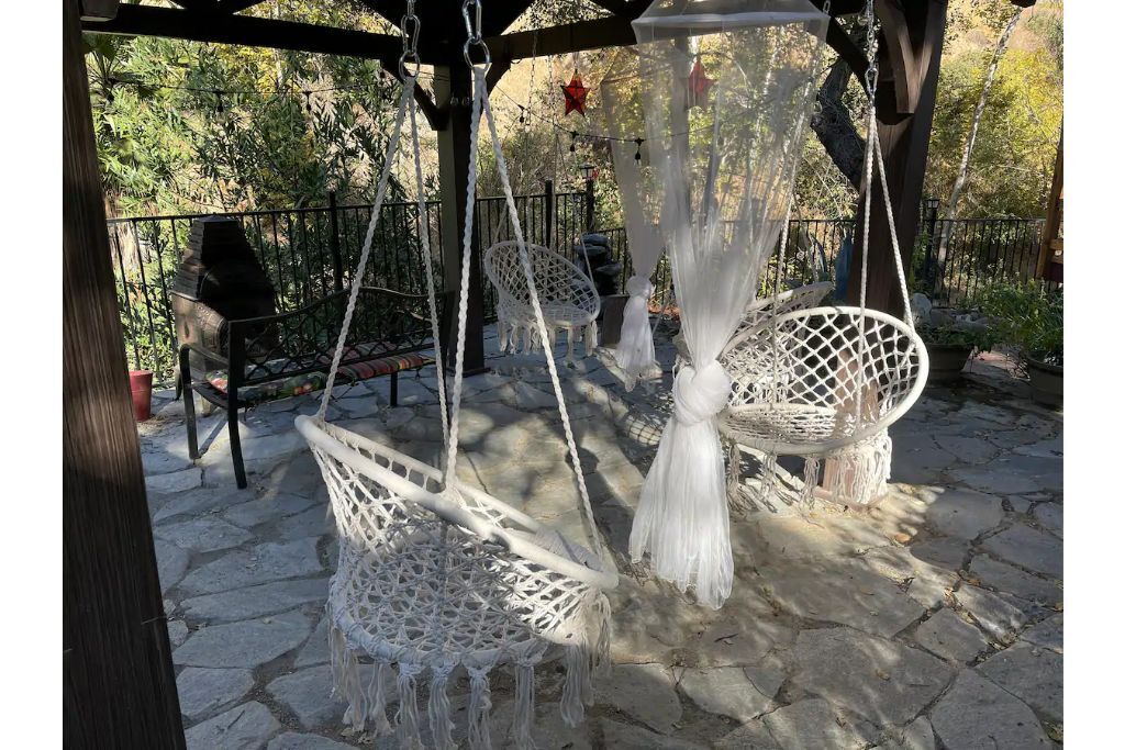 A patio with white macramé swing chairs and a hanging chair.