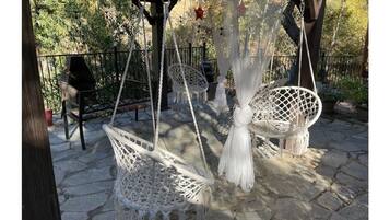 A patio with white macramé swing chairs and a hanging chair.