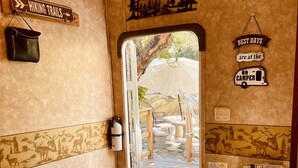 A room with a door leading to an outdoor area, a sign indicating hiking trails, a camper symbol, and a book titled 'Good Book'.
