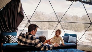 A family inside a geodesic dome with a view of a snowy landscape.