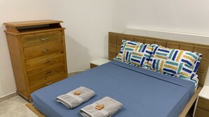 Un letto con copriletto blu, due asciugamani e cuscini decorati.