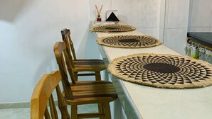 Un lungo tavolo da pranzo con una sedia di legno a un'estremità, circondato da sottopiatti intrecciati.
