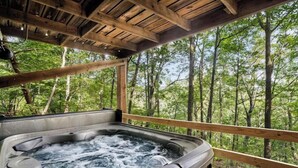 A hot tub with a wooden deck and a forest view. - Secluded Cabin: Hot Tub, Huge Deck, Fire Pit, WiFi (Hedgesville)