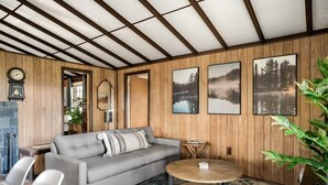 A cozy living room with a sofa, coffee table, and a fireplace. - Secluded Cabin: Hot Tub, Huge Deck, Fire Pit, WiFi (Hedgesville)