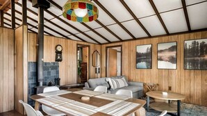 A cozy interior with a wooden dining table, chairs, a sofa, and a fireplace. - Secluded Cabin: Hot Tub, Huge Deck, Fire Pit, WiFi (Hedgesville)