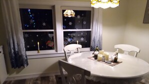 En matplats med ett runt bord, fyra stolar, ljus och en dekorativ trädgårdstomte.